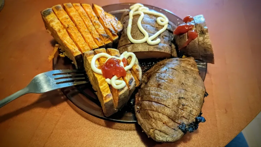 Talerz z pieczonymi ziemniakami i batatami, ozdobionymi majonezem i ketchupem.