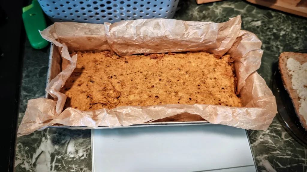Wytrawny pasztet, gotowy do wyjęcia z formy wylozonej papierem do pieczenia.