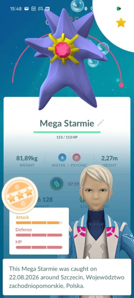 Fioletowy Pokemon w kształcie gwiazdy z żółtymi ramionami i różowym klejnotem w środku, widoczny na niebieskim tle z bańkami.
