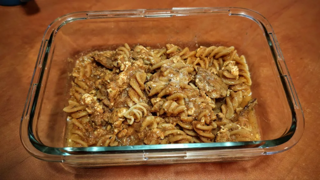 Widok z góry na makaron fusilli z mięsem i sosem w szklanym naczyniu.