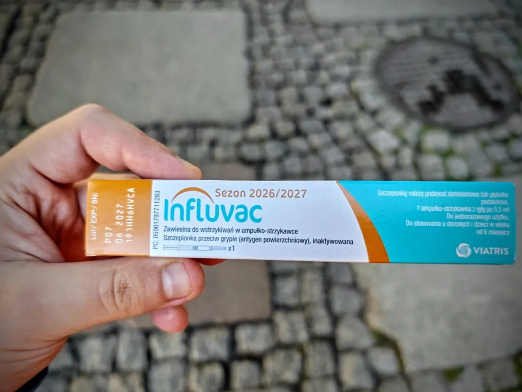 Dłoń trzymająca pudełko szczepionki przeciw grypie Influvac na sezon 2026/2027.